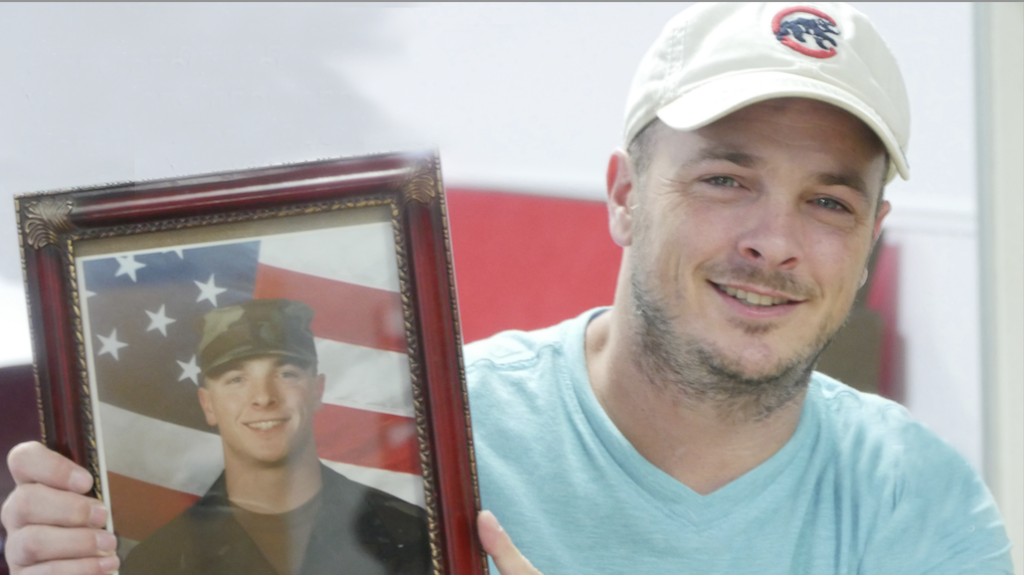 veteran smiling and holding his active duty photo
