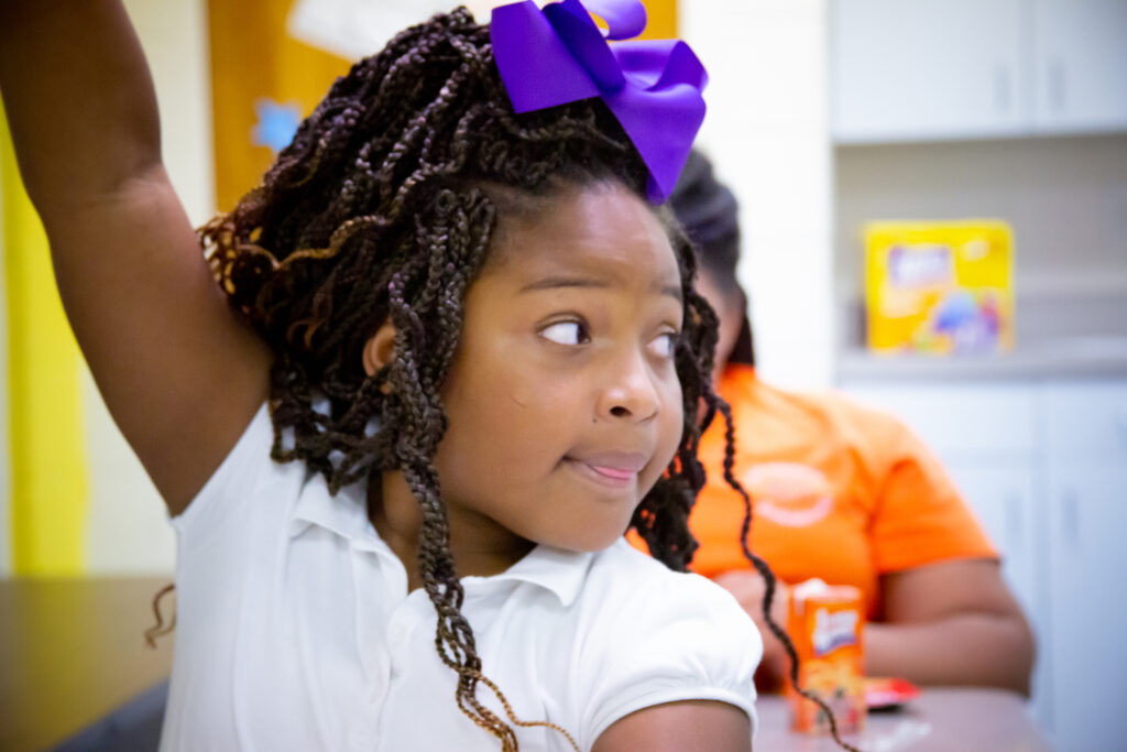 Young girl raising her hand looking left