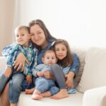 Mom and three kids hugging on a white couch