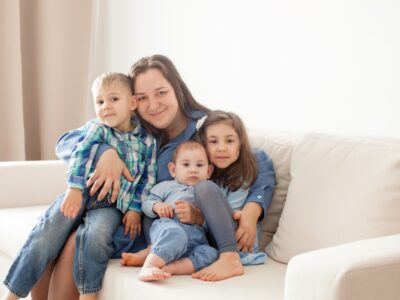 Mom and three kids hugging on a white couch